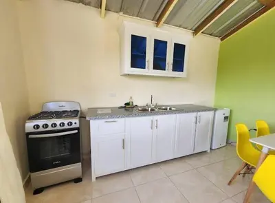 a kitchen with white cabinets and a stove and a sink at Villa Janel in Punta Rucia