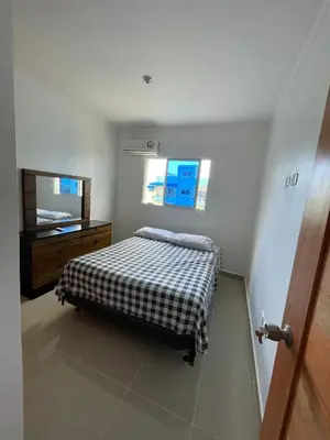 a bedroom with a bed and a dresser and a window at Comodo apartamento en Boca Chica SDQ AILA in El Higo