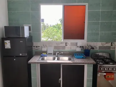 a kitchen with a sink and a refrigerator at Aparta hotel El Sol, Home near AirPort SDQ in Boca Chica