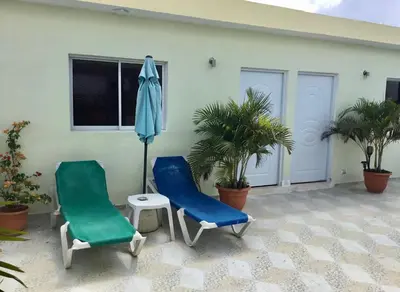 two chairs and an umbrella on a patio at Aparta hotel El Sol, Home near AirPort SDQ in Boca Chica
