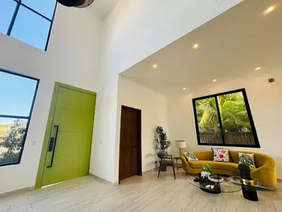 a living room with a yellow couch and a green door at Villa Aguacate Near the Beach in Juan Dolio