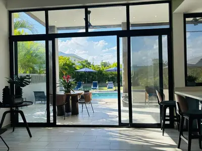 an open glass door to a patio with a pool at Villa Aguacate Near the Beach in Juan Dolio