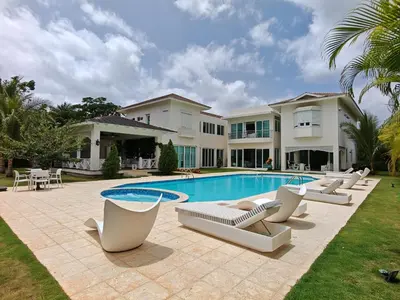 a villa with a swimming pool and lounge chairs at Casa de Campo Luxury Villa with private Pool & Jacuzzi, Near Beach, Marina, Golf, Restaurants & Altos de Chavon in La Romana