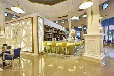 a restaurant with yellow chairs and a bar at Riu Palace Punta Cana - All Inclusive in Punta Cana