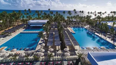 an aerial view of a resort pool with palm trees and the ocean at Riu Bambu - All Inclusive in Punta Cana