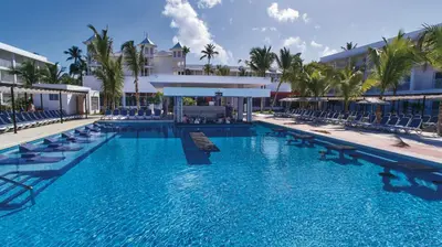 a large swimming pool with chairs and a resort at Riu Bambu - All Inclusive in Punta Cana