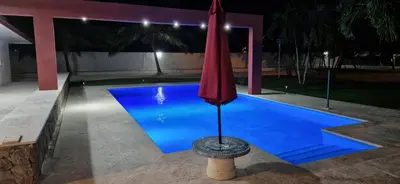 a red umbrella sitting next to a swimming pool at night at Casa Perez CCC in Juan Dolio