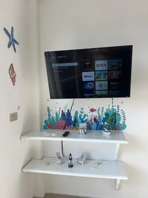 a television on a wall above a white shelf at Apartamento a solo pasos del centro y la playa in Bayahibe