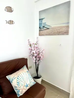 a living room with a couch and a picture of a beach at Apartamento a solo pasos del centro y la playa in Bayahibe