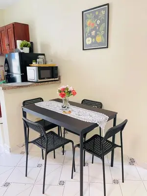 a black table with chairs and a vase of flowers on it at De pina apartaestudio in Santiago de los Caballeros