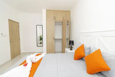 a white bedroom with orange pillows on a bed at Tranquil 2BR Retreat in Sunshine Bayahibe in San Rafael del Yuma