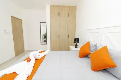 a bedroom with a white bed with orange pillows at Tranquil 2BR Retreat in Sunshine Bayahibe in San Rafael del Yuma