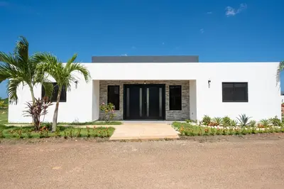 a white house with a palm tree in front of it at Location , Vibe , Style in Sosúa