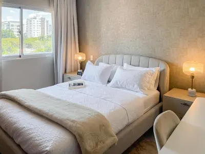 a bedroom with a large white bed with a window at Apartamento céntrico 1BR Piantini in Santo Domingo