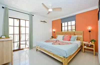 a bedroom with a bed with orange walls and windows at Tropical Retreat in El Cortecito beach condo in Punta Cana