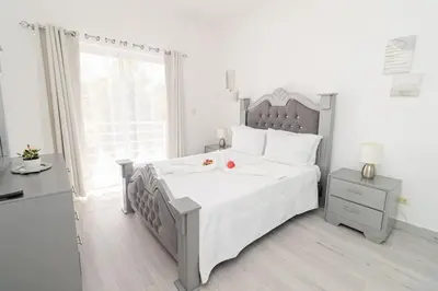 a white bedroom with a large bed and a window at Bright 2BR Apartment with Pool near Bayahibe Beach in San Rafael del Yuma