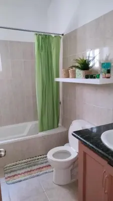 a bathroom with a toilet and a green shower curtain at Unique and quiet TROPICKÝ PRÁZDNINOVÝ DŮM in Punta Cana