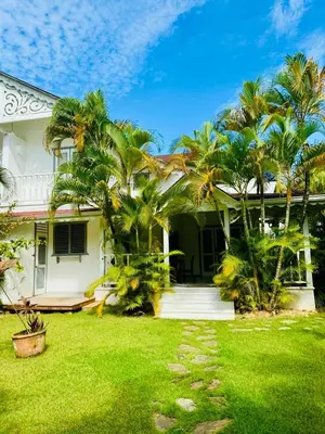 a white house with palm trees in the yard at Sole E Mare Beach House in Las Terrenas