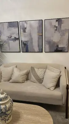 a living room with a couch with four paintings at Brand New Condo-Sunrise in Puerto Plata