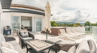 a patio with chairs and a table and an umbrella at Penthouse with jacuzzi in Lake View in Las Terrenas