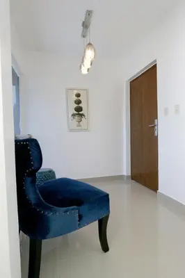 a blue chair in a room with a door at Lujoso Pent-house en el Residencial Mediterráneo in Santiago de los Caballeros
