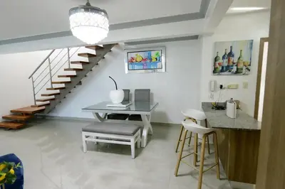 a dining room with a table and a staircase at Lujoso Pent-house en el Residencial Mediterráneo in Santiago de los Caballeros