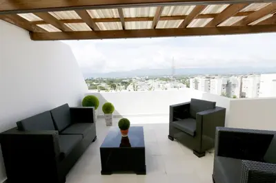 a living room with two chairs and a table at Lujoso Pent-house en el Residencial Mediterráneo in Santiago de los Caballeros