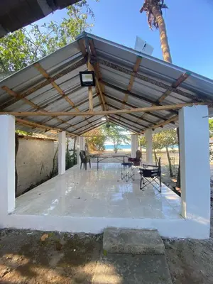 a patio with a metal roof with chairs and tables at La casa de jasinta in San Felipe de Puerto Plata