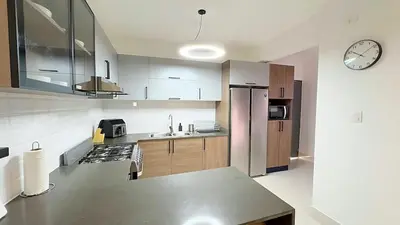 a kitchen with stainless steel appliances and a clock on the wall at Luxury Apartment-PRIVATE Patio & BBQ-Near Airport in Santiago de los Caballeros