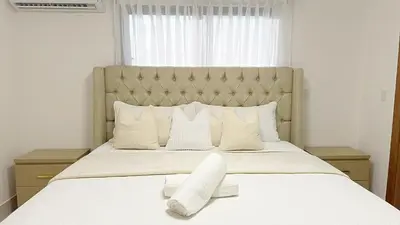 a bedroom with a large bed with white sheets and pillows at Luxury Apartment-PRIVATE Patio & BBQ-Near Airport in Santiago de los Caballeros