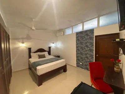 a bedroom with a bed and a red chair at Hotel Down Town Cabrera in Cabrera