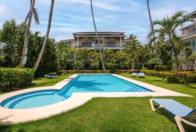 a swimming pool in the yard of a house with palm trees at Casa Zelima, a fully equipped apartment in Las Terrenas