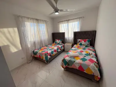two beds in a room with two windows at Ocean View Apartment in Santo Domingo Este in La Viva