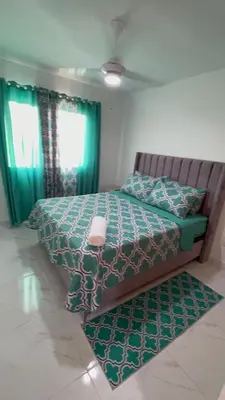 a bedroom with a bed with a green comforter at Ocean View Apartment in Santo Domingo Este in La Viva