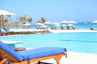 a swimming pool with chairs and umbrellas on a beach at Cana Cove in Punta Cana