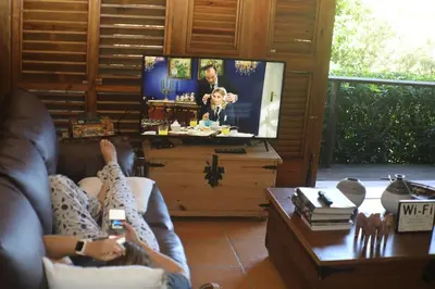 a woman laying on a couch watching a tv at Villa del Pino en Quintas del Bosque in Jarabacoa