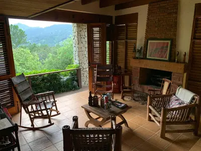 a living room with rocking chairs and a fireplace at Villa del Pino en Quintas del Bosque in Jarabacoa