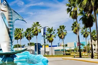 a statue of a fish in a fountain with palm trees at Condominio con piscina, cerca de la playa in Punta Cana