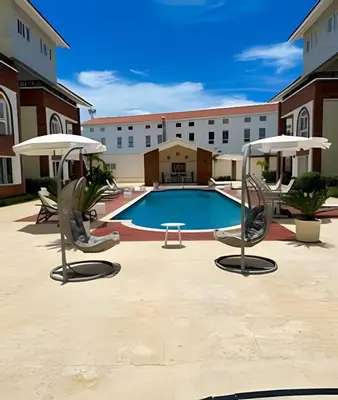 a pool with chairs and umbrellas in a courtyard at Alojamientos de 1 y 2 habitaciones a 5 min de la playa in Punta Cana