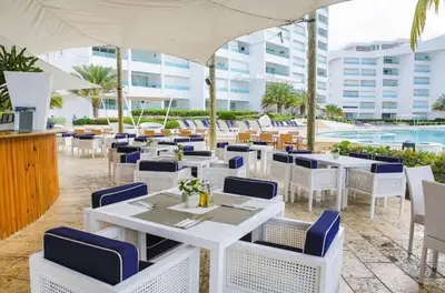 a restaurant with white tables and blue chairs at Beachfront Three Bedroom apt with Jacuzzi in Juan Pedro