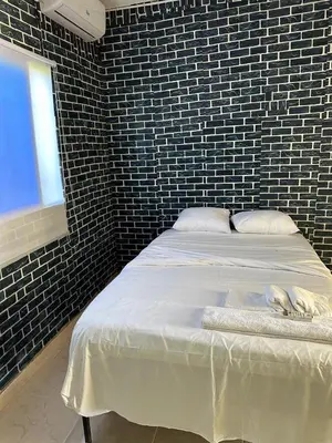 a bedroom with a white bed with a brick wall at Aparta El Mundo in Punta Cana