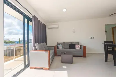a living room with a couch and a balcony at Modern Serviced Apartment with Free Wi-Fi, 24h Power & Private Parking in Sosúa