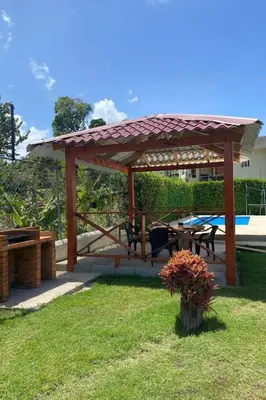 a wooden gazebo with a picnic table and bench at Modern Serviced Apartment with Free Wi-Fi, 24h Power & Private Parking in Sosúa
