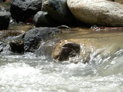 a stream of water with rocks in a river at Eco Camping Jarabacoa in Jarabacoa