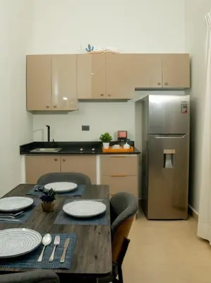 a kitchen with a wooden table with chairs and a refrigerator at Ocean Winds Hotel in San Felipe de Puerto Plata