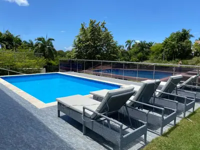 a swimming pool with chairs and a table next to it at Villa Tula in Sosúa