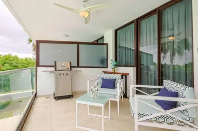 a balcony with chairs and a table and a tv at Comfy Retreat Balcony Grill Pool in Punta Cana