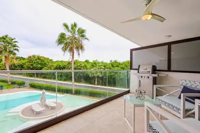 a living room with a view of a swimming pool at Comfy Retreat Balcony Grill Pool in Punta Cana