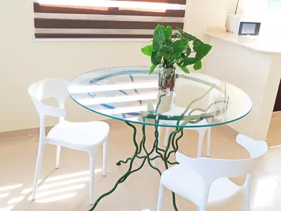 a glass table with white chairs and a vase with a plant at Apartamento en Residencial Los Pinos Cotui in Cotuí