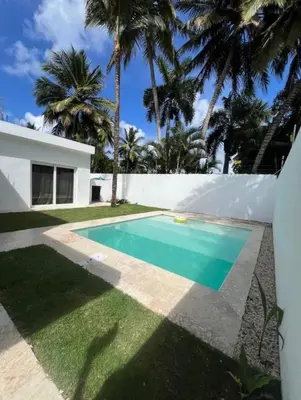 a swimming pool in the backyard of a house with palm trees at Villa Iana BN in Puerto Plata